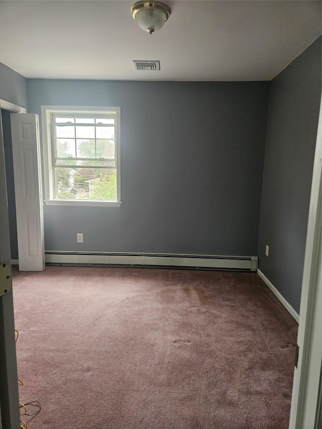 carpeted spare room featuring a baseboard heating unit and baseboards