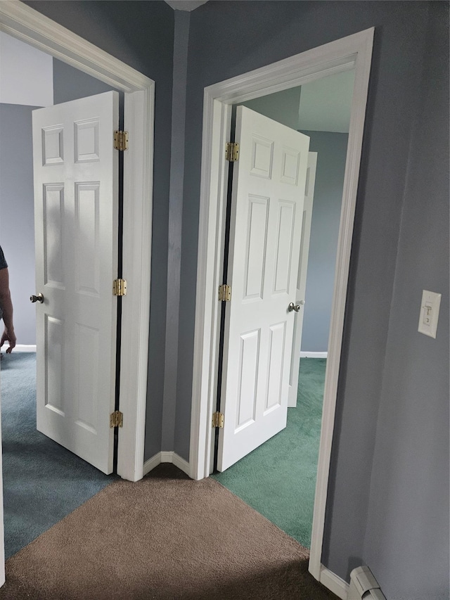 hall with dark carpet, baseboards, and baseboard heating