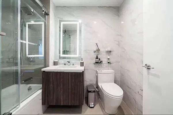 134-37 35th Ave Unit 8E, Flushing, NY 11354 - full bathroom featuring toilet, tile walls, combined bath / shower with glass door, and vanity