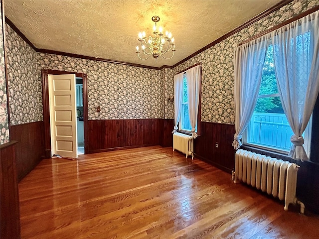 22 Herbert St, Beacon, NY 12508 - unfurnished room with radiator heating unit, wood finished floors, a chandelier, a wainscoted wall, and a textured ceiling
