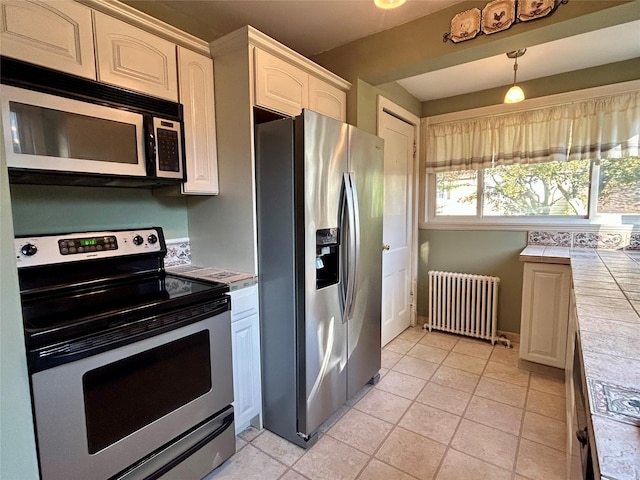 22 Herbert St, Beacon, NY 12508 - kitchen with radiator heating unit, stainless steel appliances, tile counters, light tile patterned flooring, and pendant lighting