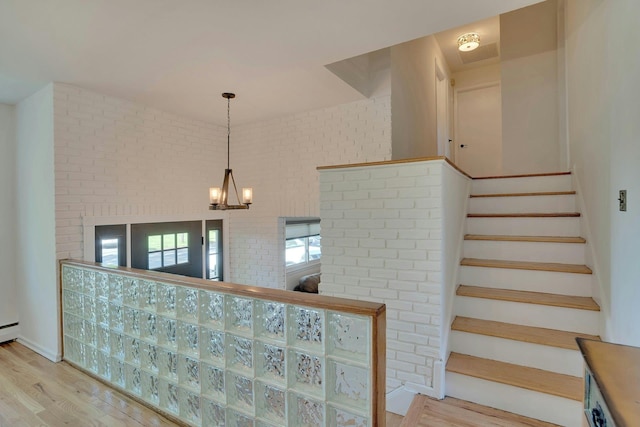 24 Harvard Ln, Commack, NY 11725 - stairs with wood finished floors, a chandelier, brick wall, and baseboards