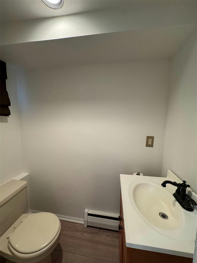 24 Harvard Ln, Commack, NY 11725 - half bath featuring a baseboard radiator, wood finished floors, toilet, vanity, and baseboards