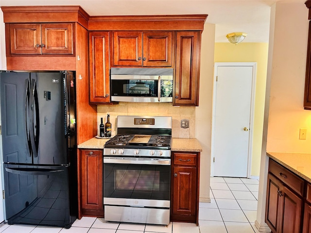 1 Olde Wagon Rd, Warwick, NY 10990 - kitchen featuring appliances with stainless steel finishes, light tile patterned floors, light stone countertops, and brown cabinets