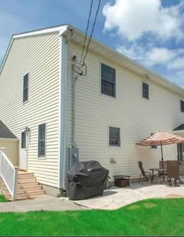 rear view of house with a patio area and a lawn