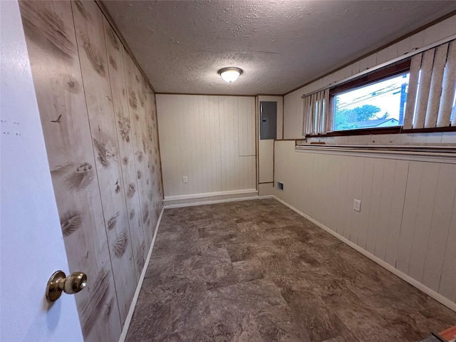 42 Blacker St, Brentwood, NY 11717 - spare room featuring baseboards, electric panel, wooden walls, and a textured ceiling