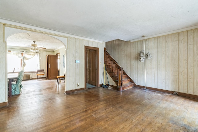 179-03 Selover Rd, Jamaica, NY 11434 - unfurnished living room with arched walkways, wood-type flooring, stairway, wooden walls, and baseboards