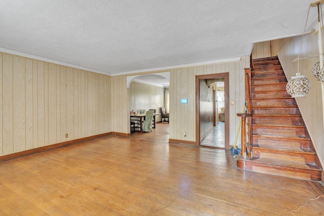 179-03 Selover Rd, Jamaica, NY 11434 - unfurnished living room with arched walkways, wood finished floors, stairs, crown molding, and a textured ceiling