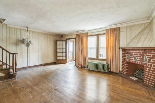 179-03 Selover Rd, Jamaica, NY 11434 - unfurnished living room with radiator, wood-type flooring, a textured ceiling, a fireplace, and stairs