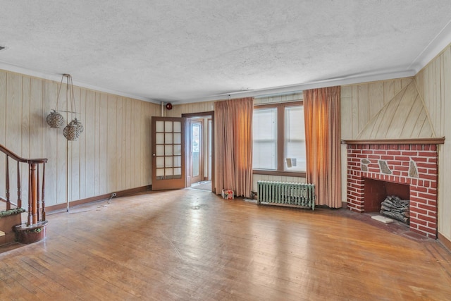 179-03 Selover Rd, Jamaica, NY 11434 - unfurnished living room with radiator heating unit, hardwood / wood-style floors, a fireplace, a textured ceiling, and stairway