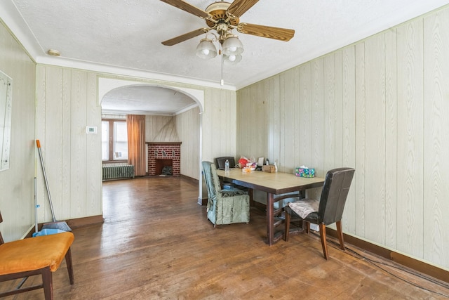 179-03 Selover Rd, Jamaica, NY 11434 - dining area with radiator, arched walkways, wood finished floors, a brick fireplace, and a textured ceiling