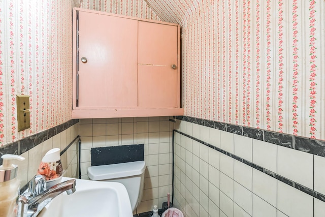 179-03 Selover Rd, Jamaica, NY 11434 - half bathroom featuring wallpapered walls, toilet, wainscoting, a sink, and tile walls