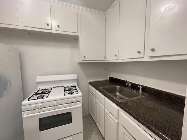 108-49 63rd Dr Unit 1K, Forest Hills, NY 11375 - kitchen featuring white range with gas stovetop, white cabinets, dark countertops, and light tile patterned floors
