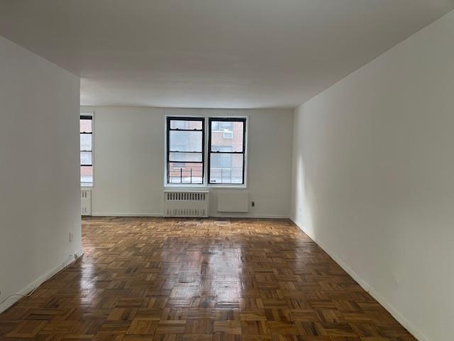 108-49 63rd Dr Unit 1K, Forest Hills, NY 11375 - spare room with radiator heating unit and healthy amount of natural light