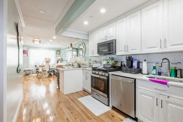 23118 145th Ave, Springfield Gardens, NY 11413 - kitchen featuring stainless steel appliances, ornamental molding, white cabinets, decorative backsplash, and light wood-type flooring