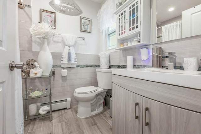 23118 145th Ave, Springfield Gardens, NY 11413 - bathroom featuring tile walls, toilet, a baseboard heating unit, vanity, and wood finished floors