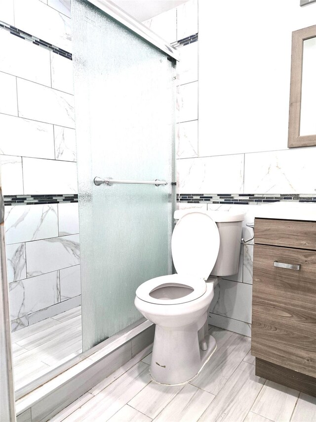 23118 145th Ave, Springfield Gardens, NY 11413 - bathroom featuring toilet, a stall shower, vanity, and tile walls