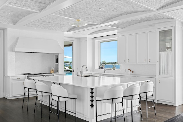 34 Westbridge Rd, Westhampton Beach, NY 11978 - kitchen featuring dark wood-style flooring, white cabinetry, a kitchen bar, light countertops, and a center island with sink