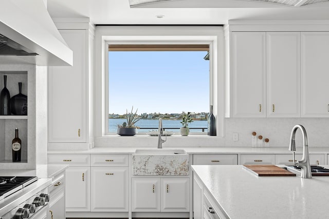34 Westbridge Rd, Westhampton Beach, NY 11978 - kitchen with a sink, white cabinets, a water view, range, and wall chimney exhaust hood