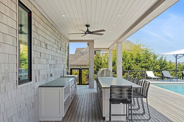 34 Westbridge Rd, Westhampton Beach, NY 11978 - deck featuring grilling area, ceiling fan, an outdoor pool, exterior kitchen, and a sink