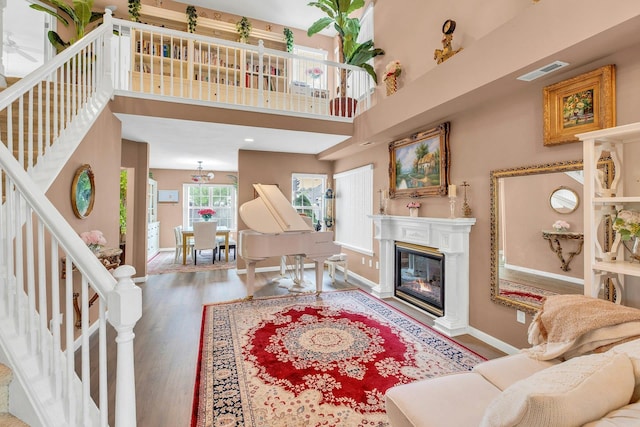 7 Marisa Dr, Middle Island, NY 11953 - living area with wood finished floors, baseboards, a glass covered fireplace, stairway, and a high ceiling