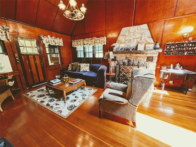11 W Mongaup Trl, Smallwood, NY 12778 - living area with hardwood / wood-style flooring, wooden walls, a chandelier, lofted ceiling, and a stone fireplace