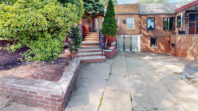 48-17 54th Ave, Maspeth, NY 11378 - view of front of home with a shingled roof, brick siding, and mansard roof