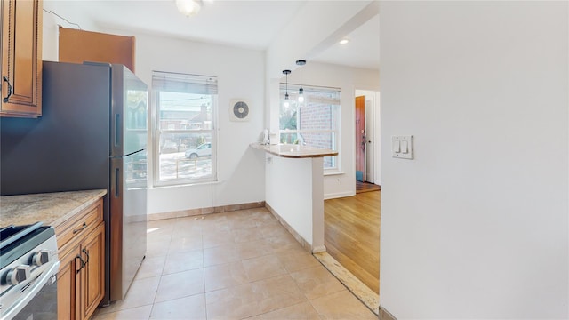 48-17 54th Ave, Maspeth, NY 11378 - kitchen featuring appliances with stainless steel finishes, brown cabinets, light tile patterned floors, baseboards, and decorative light fixtures