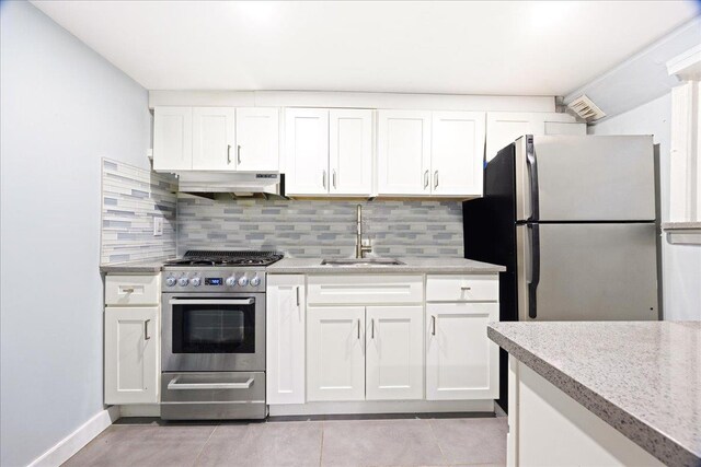 kitchen with a sink, stainless steel appliances, under cabinet range hood, backsplash, and white cabinetry