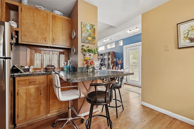 42 Longview Ave, White Plains, NY 10605 - kitchen featuring light wood-style floors, freestanding refrigerator, baseboards, a kitchen bar, and dark countertops