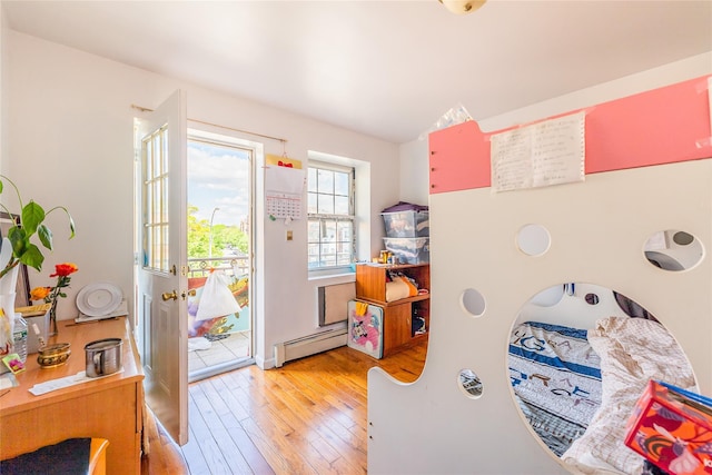 bedroom featuring a baseboard heating unit, access to exterior, and light wood-style floors