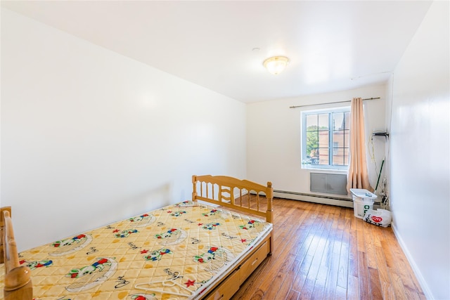 bedroom featuring baseboard heating, light wood-type flooring, and baseboards
