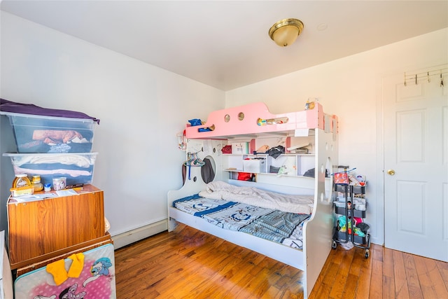 bedroom with a baseboard heating unit and hardwood / wood-style flooring
