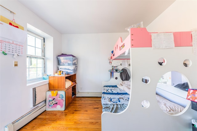 bedroom featuring a baseboard heating unit, light wood-style flooring, and baseboard heating