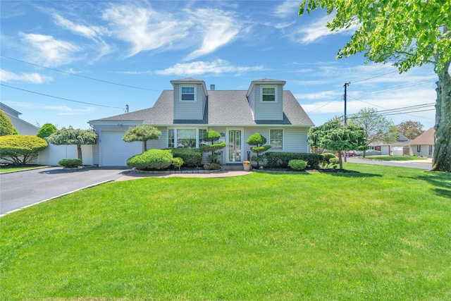 view of front of home featuring an attached garage, driveway, a front yard, and roof with shingles