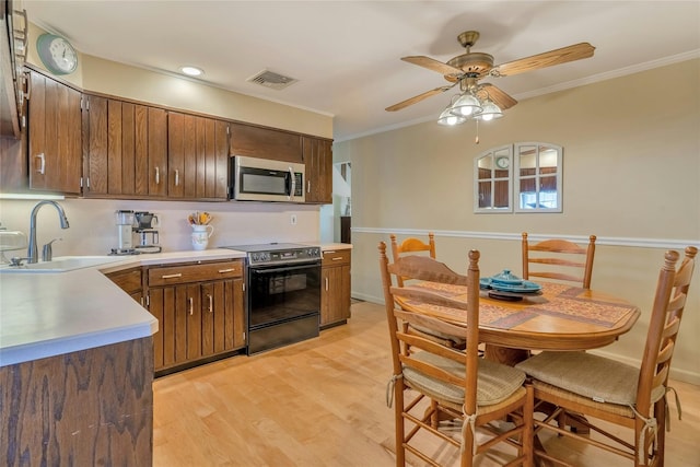 kitchen with stainless steel microwave, electric range oven, a sink, light countertops, and crown molding