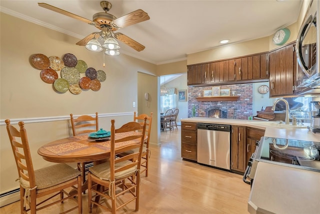 kitchen with stainless steel appliances, a sink, ceiling fan, light countertops, and light wood-style floors