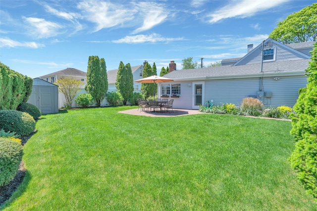 view of grassy yard featuring a storage unit, an outbuilding, and a patio area