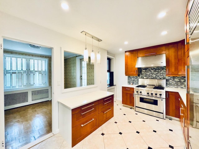 kitchen with exhaust hood, stainless steel stove, brown cabinetry, light countertops, and backsplash