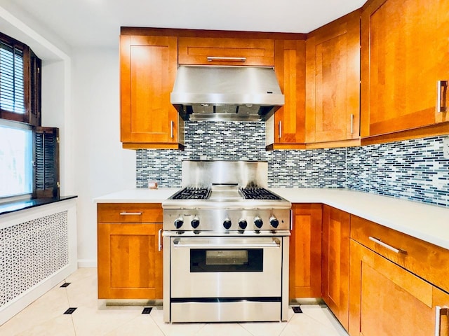 kitchen with wall chimney exhaust hood, high end stainless steel range oven, brown cabinets, light countertops, and radiator heating unit