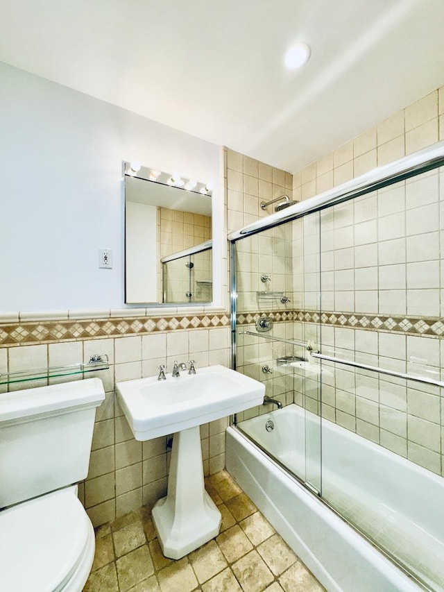 bathroom featuring tile walls, enclosed tub / shower combo, toilet, and recessed lighting