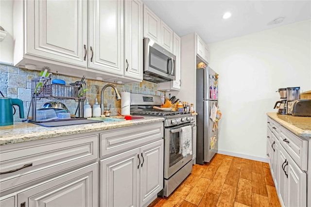13-10 212th St Unit 118, Bayside, NY 11360 - kitchen with stainless steel appliances, white cabinetry, decorative backsplash, light wood finished floors, and recessed lighting