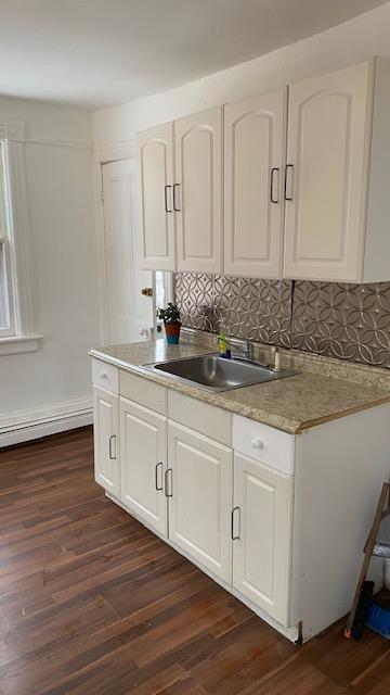 kitchen featuring a sink, dark wood finished floors, white cabinetry, decorative backsplash, and light countertops