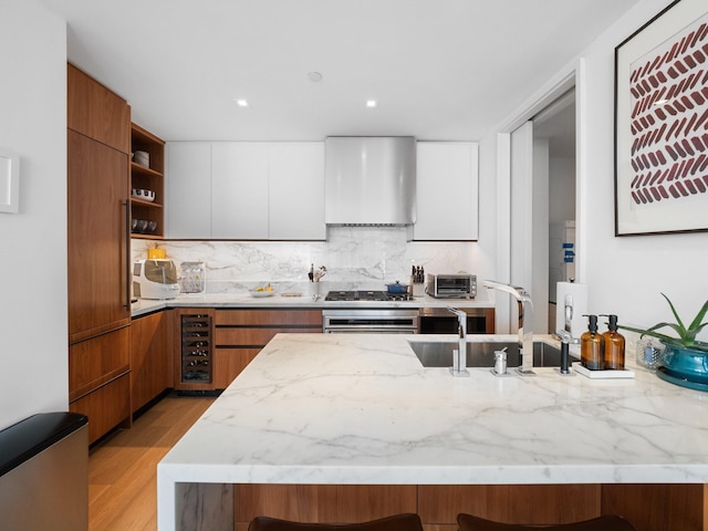 1 W End Ave Unit 26D, New York Manhattan, NY 10023 - kitchen featuring wall chimney range hood, modern cabinets, open shelves, light stone countertops, and a breakfast bar area