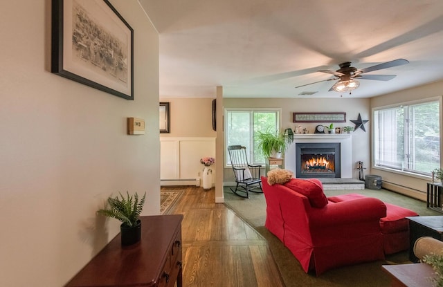 15 Marshall Dr, Poughkeepsie, NY 12601 - living room with a baseboard radiator, a warm lit fireplace, a ceiling fan, and wood finished floors
