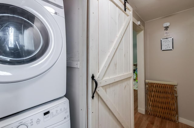 15 Marshall Dr, Poughkeepsie, NY 12601 - clothes washing area with a barn door, stacked washer / drying machine, and wood finished floors
