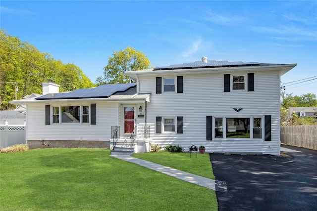 view of front of property with roof mounted solar panels and a chimney