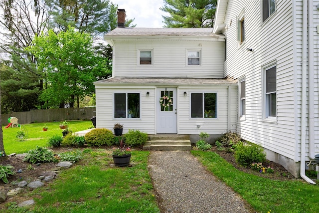 entrance to property featuring a chimney and roof with shingles
