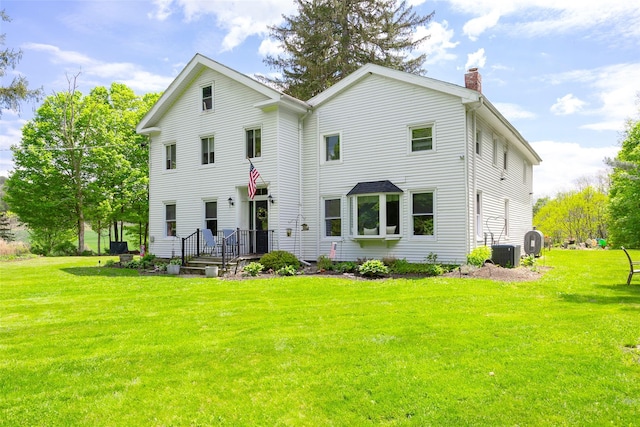 view of front of house with a chimney, a front yard, and cooling unit