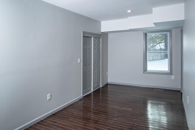 empty room featuring wood finished floors, baseboards, and recessed lighting